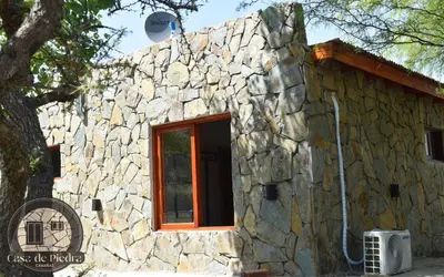 a stone building with a window and a tree at Cabañas Casa de Piedra Los Molles - San Luis in Los Molles