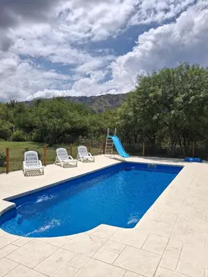a swimming pool with chairs and a slide at Cabañas Casa de Piedra Los Molles - San Luis in Los Molles