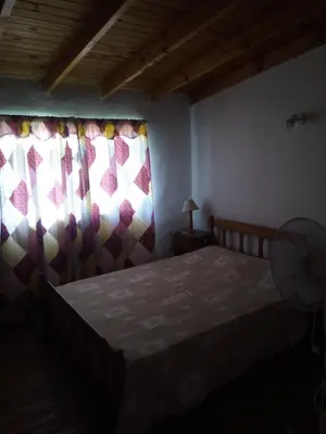 a bedroom with a bed and curtains and a fan at Lo de Juan Cabañas in Los Reartes