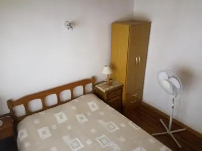 a bedroom with a bed and a desk with a fan at Lo de Juan Cabañas in Los Reartes
