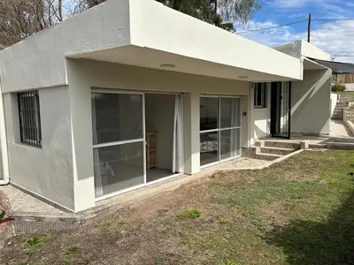 a white house with glass doors in a yard at Casa de Ali in Villa Carlos Paz