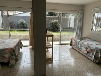 a bedroom with two beds and a table and a window at Casa de Ali in Villa Carlos Paz