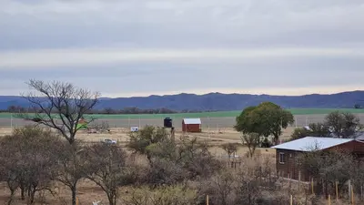 a field with a house and trees and mountains in the background at Aromas serranos in Villa Rumipal