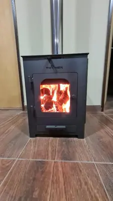 a black stove with a fire in a room at Aromas serranos in Villa Rumipal