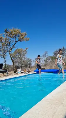 two young boys are standing on a swimming pool at Aromas serranos in Villa Rumipal