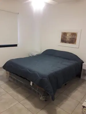 a bed in a white room with a blue blanket at Depto amoblado en el centro de la capital de cordoba in Cordoba