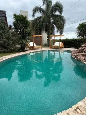 a large blue swimming pool with two chairs and palm trees at Dinastie Country in Villa Rumipal