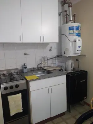 a kitchen with white cabinets and a stove and a sink at Departamento en Nueva Córdoba in Cordoba