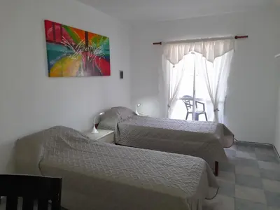 a bedroom with two beds and a window with a chair at CELESTINA in Cordoba