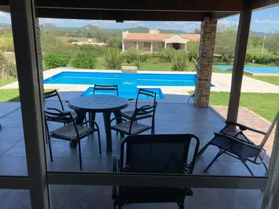 a patio with a table and chairs and a pool at Casa con vista a las sierras de Cordoba in Malagueño