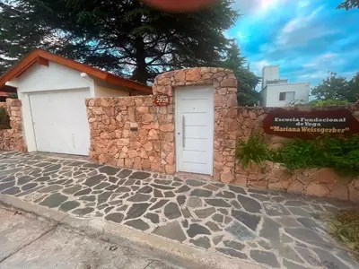 a building with a stone wall with a garage at Ashram Asociación Argentina de Yoga in Mina Clavero