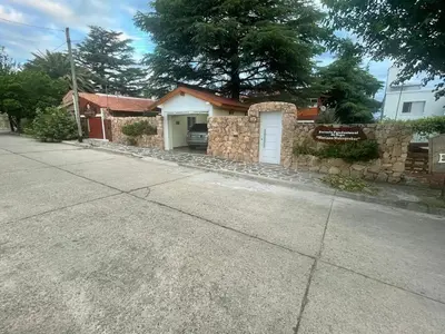 a house with a stone wall and a white garage at Ashram Asociación Argentina de Yoga in Mina Clavero