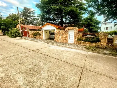 a brick house with a white door and a stone wall at Ashram Asociación Argentina de Yoga in Mina Clavero