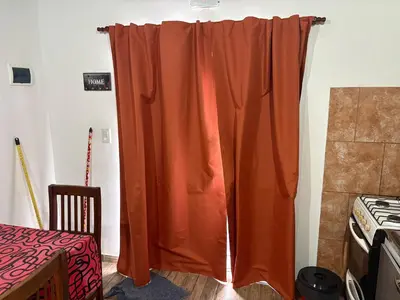 an orange curtain in a room with a stove at Departamento Genaro in Mina Clavero