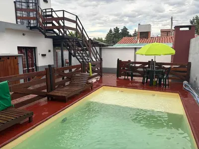 a swimming pool on a patio with a table and an umbrella at Departamento Genaro in Mina Clavero