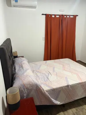 a bed in a room with a red curtain at Departamento Genaro in Mina Clavero