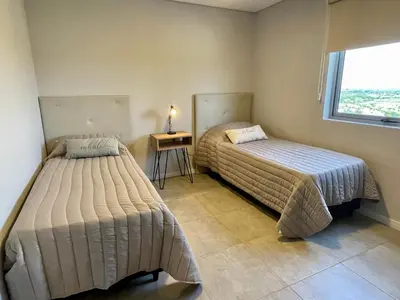 two beds in a room with a table and a window at Rent a Flat - Río Cuarto in Río Cuarto