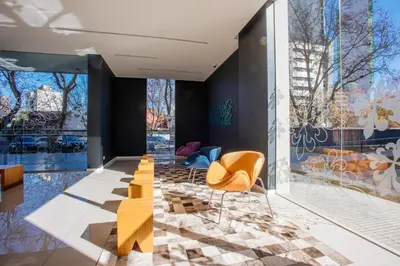 a lobby with yellow chairs and a wall of windows at Rent a Flat - Río Cuarto in Río Cuarto