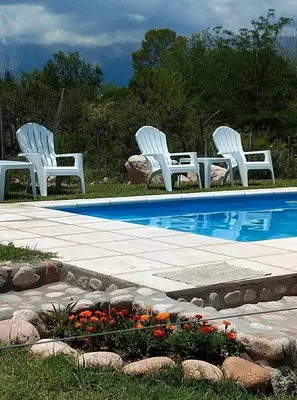 three white chairs sitting next to a swimming pool at Cabañas Paraje Noviembre in Nono
