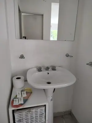 a white bathroom with a sink and a mirror at Departamento W R T 1 in Villa Carlos Paz