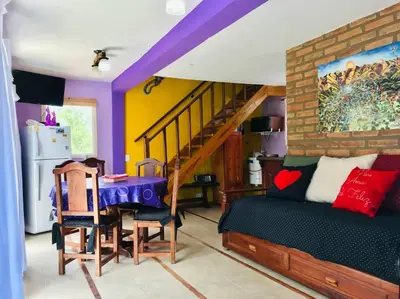 a living room with a table and a dining room at CABAÑA LA MILAGROS REINA MORA in Merlo