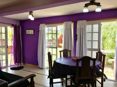 a dining room with purple walls and a table at CABAÑA LA MILAGROS REINA MORA in Merlo