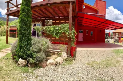 a red building with a bench in front of it at CABAÑA LA MILAGROS REINA MORA in Merlo