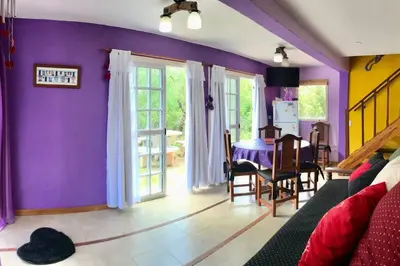 a living room with purple walls and a table and chairs at CABAÑA LA MILAGROS REINA MORA in Merlo