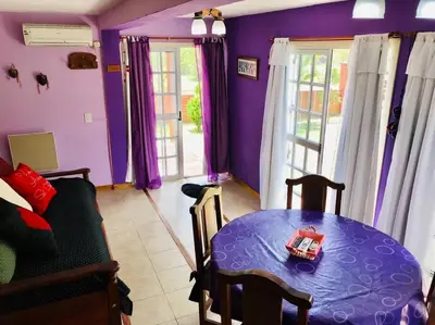 a living room with a table and purple walls at CABAÑA LA MILAGROS REINA MORA in Merlo
