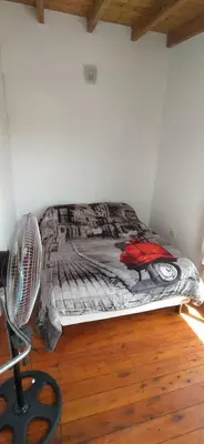 a bed in a room with a fan on the floor at Cabaña Nerviomotor in Cordoba