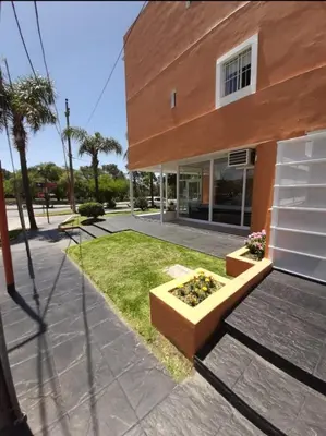 a building with a bench in front of a yard at Saint Tropez Hotel in Villa Carlos Paz