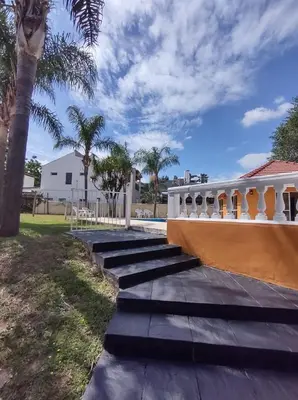 a walkway next to a house with palm trees at Saint Tropez Hotel in Villa Carlos Paz
