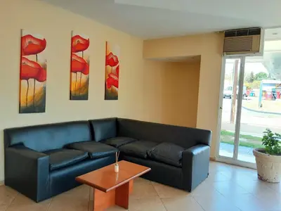 a living room with a black couch and paintings on the wall at Saint Tropez Hotel in Villa Carlos Paz