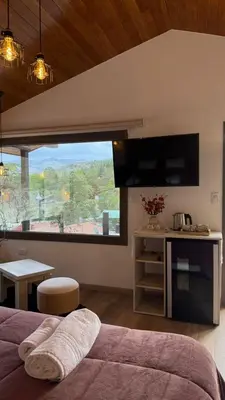 a bedroom with a bed and a large window at Vimaen Suites in La Cumbrecita