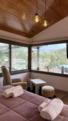 a bedroom with a large bed and a large window at Vimaen Suites in La Cumbrecita