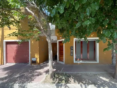 a yellow house with a red door and a tree at Encantador Duplex cerca de todo in Cordoba