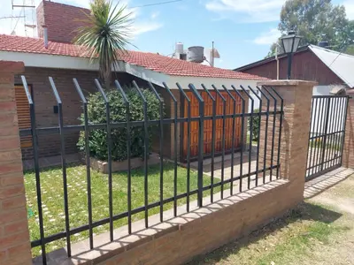 an iron fence with a palm tree behind it at Aire Serrano in Alta Gracia