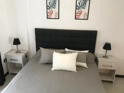 a large bed with a black headboard and two night stands at Departamento céntrico Villa Carlos Paz in Villa Carlos Paz
