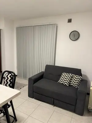 a black couch in a living room with a clock on the wall at Departamento céntrico Villa Carlos Paz in Villa Carlos Paz