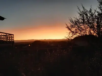 a sunset over the mountains with a tree in the foreground at MiraSierras -casas vacacionales- in Villa General Belgrano