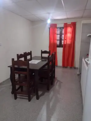a dining room with a table and chairs and red curtains at Complejo de Departamentos DON QUIJOTE in Almafuerte