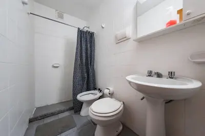 a white bathroom with a toilet and a sink at Marcelo T de Alvear 628 - B Güemes con Vistas a la Cañada in Cordoba
