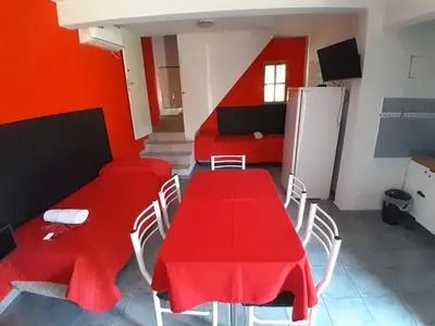 a room with a red table and chairs and a refrigerator at Apart Hotel Nonquen in Merlo