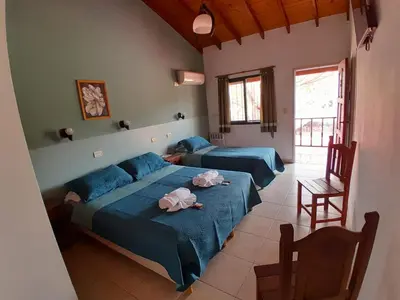 a bedroom with two beds and a chair at Apart Hotel Nonquen in Merlo