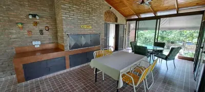 a living room with a table and chairs and a tv at La Calma, casa frente al río, gran parque y pileta in Villa Icho Cruz