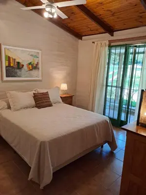 a bedroom with a bed and a large window at La Calma, casa frente al río, gran parque y pileta in Villa Icho Cruz