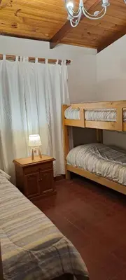 a bedroom with two bunk beds and a table with a lamp at La Calma, casa frente al río, gran parque y pileta in Villa Icho Cruz