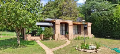 a small brick house in a yard with a tree at La Calma, casa frente al río, gran parque y pileta in Villa Icho Cruz