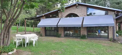 a table and chairs in front of a building at La Calma, casa frente al río, gran parque y pileta in Villa Icho Cruz