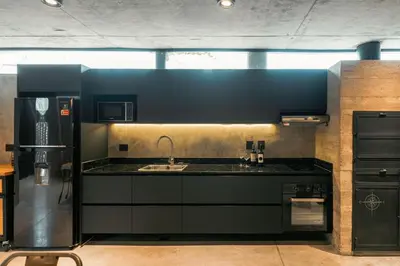 a kitchen with black cabinets and a sink and a refrigerator at Loft 1930 in Villa Carlos Paz